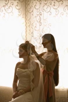 Royalty Free Photo of a Bridesmaid Placing a Veil on a Bride