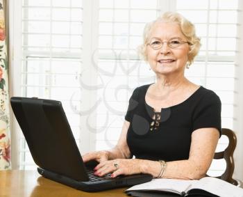 Mature Caucasian woman using laptop in living room.