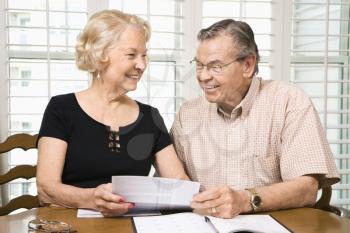 Mature Caucasian couple looking at their bills.