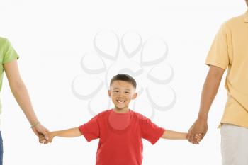 Asian parents holding hands with son in front of white background.
