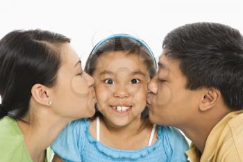 Royalty Free Photo of a Mother and Father Kissing Opposite Cheeks of Their Smiling Daughter