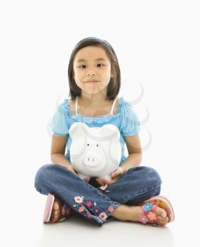 Royalty Free Photo of a Girl Sitting on a Floor Holding a Piggy-bank 