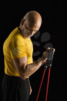 Royalty Free Photo of a Man Exercising With a Stretch Band and Looking at Bicep