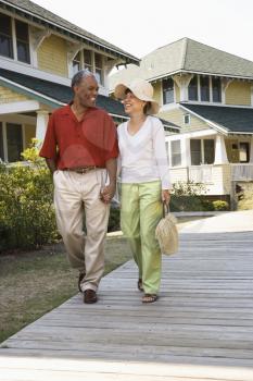 Royalty Free Photo of a Couple Holding Hands Strolling on a Wooden Walkway