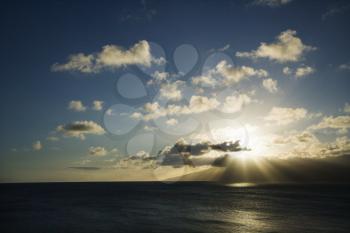 Royalty Free Photo of Pacific Ocean and Island With Sun Streaming Through Clouds