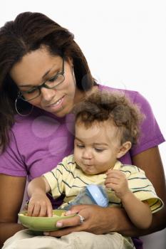 Royalty Free Photo of a Mom Sitting With Toddler Son on Her Lap Eating Cereal