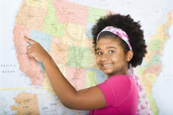 African American girl pointing to map of United States and smiling at viewer.