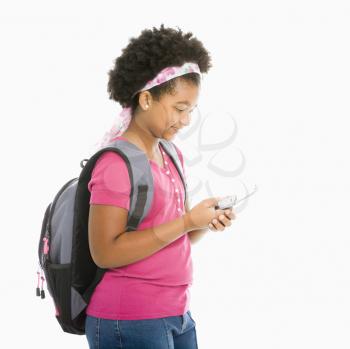 African American girl with backpack text messaging on cell phone.