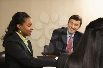 Royalty Free Photo of Businesspeople Sitting at a Conference Table Talking and 
Smiling