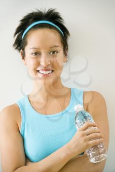 Royalty Free Photo of a Young Woman in Exercise Clothes Holding a Bottle of Water Smiling