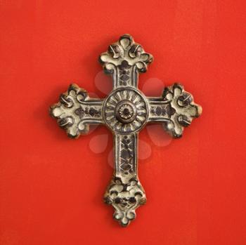 Royalty Free Photo of an Ornate Religious Cross Hanging on a Red Wall
