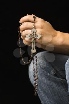 Woman's hands holding rosary with crucifix.