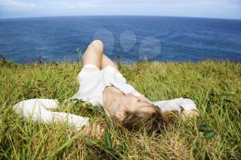 Royalty Free Photo of a Woman Relaxing in the Grass Above the Ocean in Maui, Hawaii