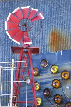 Royalty Free Photo of an Old Red Broken Windmill Against a Building Covered in Taillights