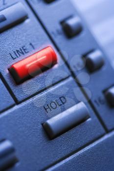 Close up of a multi-line office telephone with lit line one button. Vertical shot.