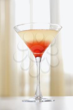 Mixed drink in a martini glass with red settling at the bottom Vertical shot.