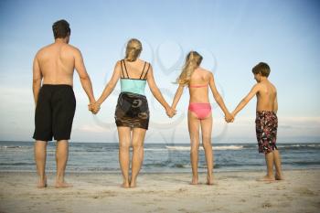 Rear view of a family holding hands at the beach. Horizontal shot.