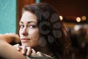 Closeup portrait of a young woman resting her arms on a windowsill. Horizontal shot.
