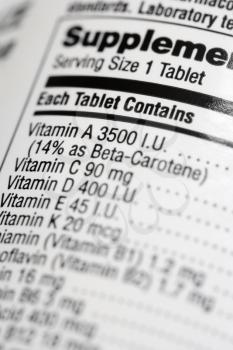 Closeup of a dietary supplement label listing the vitamins contained within each tablet. Vertical shot.