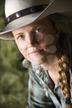 Attractive young woman with braided hair and wearing a cowboy hat. Vertical shot.