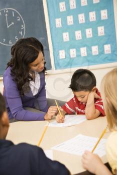 Teacher assisting young male student with lesson. Vertically framed shot.