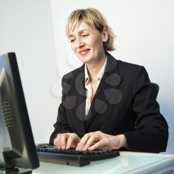 Caucasian businesswoman typing on computer keyboard smiling.