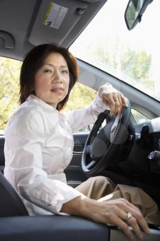 Asian woman driver sitting in car at steering wheel.