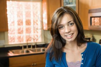 Pretty Caucasian young woman smiling in kitchen.