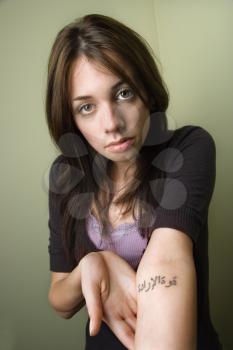 Pretty young Caucasian woman showing tattoo on arm.