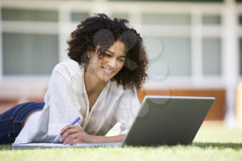 Royalty Free Photo of a Woman Lying on the Lawn With a Laptop