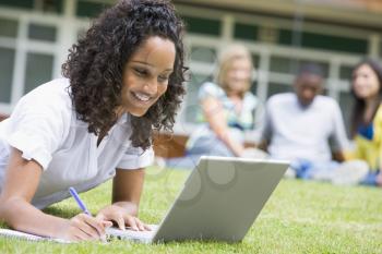 Royalty Free Photo of a Student Working on a Laptop With Others Behind Her