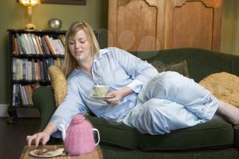 Royalty Free Photo of a Young Woman Eating Cookies and Drinking Tea