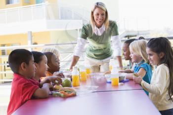 Royalty Free Photo of Students Eating Lunch and the Teacher at the Table