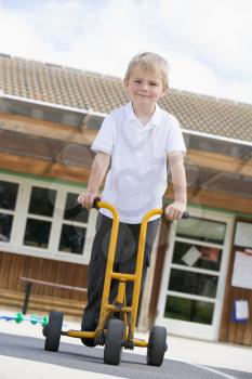 Royalty Free Photo of a Child Outside a School on a Scooter