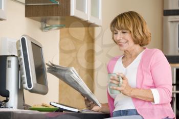 Royalty Free Photo of a Woman With Coffee and a Newspaper at the Computer