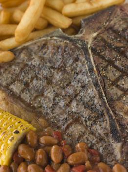 Royalty Free Photo of a T-Bone Steak with Fries, Corn and Beans