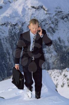 Royalty Free Photo of a Businessman on a Mountain With a Cellphone