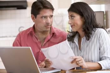 Royalty Free Photo of a Couple With a Laptop Looking Worried at a Paper
