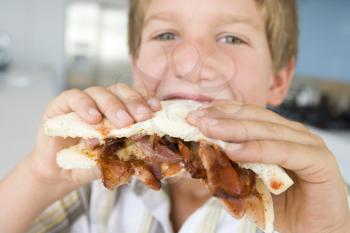 Royalty Free Photo of a Boy Eating a Bacon Sandwich