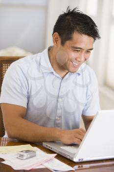 Royalty Free Photo of a Man With a Laptop at a Dining Room Table