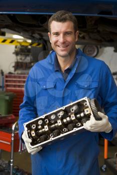 Royalty Free Photo of a Mechanic Holding a Car Part