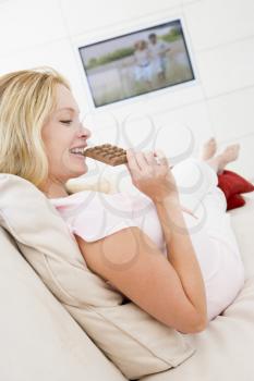 Royalty Free Photo of a Pregnant Woman Eating Chocolate in Front of the TV