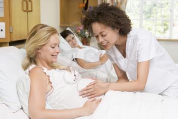 Royalty Free Photo of a Nurse Checking a Pregnant Woman's Belly