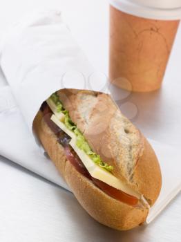 Royalty Free Photo of a Cheddar Cheese, Pickle And Salad Baguette With A Take Away Coffee