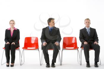 Three Business People Sitting On Red Plastic Seats 