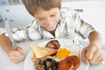 Royalty Free Photo of a Boy Eating Bacon and Eggs