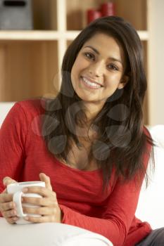 Young Woman Sitting On Sofa With Cup Of Coffee