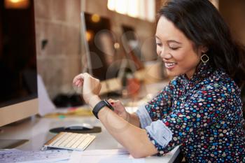 Businesswoman Looking At Smart Watch In Design Office