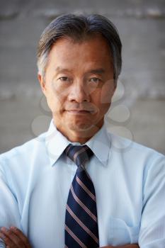 Asian Businessman Standing Against Wall In Modern Office