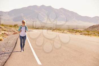 Woman On Vacation Hitchhiking Along Country Road